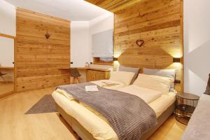 een slaapkamer met een groot bed en een houten muur bij Iride Villa Nordica in Livigno