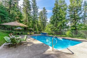 a swimming pool with chairs and a table and an umbrella at Wooded Dreams in Whitefish