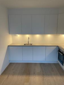 a kitchen with white cabinets and a sink at Helt ny leilighet med flott beliggenhet nært havet in Tromsø