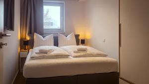 Un dormitorio con una cama con almohadas blancas y una ventana en Gebirgsresort - Ferienwohnung Schanzenblick, en Winterberg