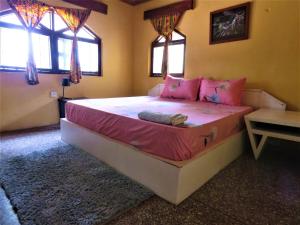 a bedroom with a large bed with pink pillows at Private Beachfront Home-Ocean View-Total Privacy in Ampeni