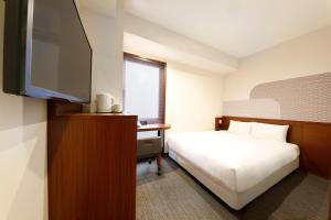 a hotel room with a bed and a flat screen tv at Hop Inn Kyoto Shijo Omiya in Kyoto