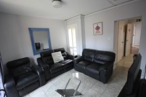 a living room with black leather furniture and a mirror at Rockingham House Uxbridge in Uxbridge