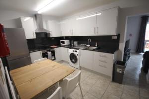 a kitchen with white cabinets and a wooden table at Rockingham House Uxbridge in Uxbridge
