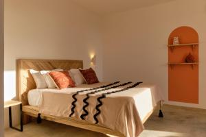 Ngaring的住宿－Kawga Hôtel，一间卧室配有一张带橙色和白色枕头的大床