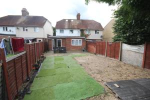 a backyard with a fence and a yard withgrass at Rockingham House Uxbridge in Uxbridge