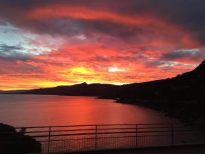 um pôr-do-sol sobre um corpo de água com uma cerca em Blue Bay em Cefalù