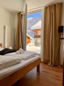 - une chambre avec un lit et une grande fenêtre dans l'établissement Mountain View Apartment, à Kandersteg