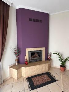 a living room with a fireplace with a purple wall at Bakopoulos resort.Ενα όμορφο διαμέρισμα με τζάκι in Tríkala