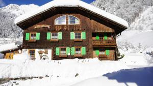 una casa cubierta de nieve frente a una montaña en Haus Älpele, en Klösterle am Arlberg