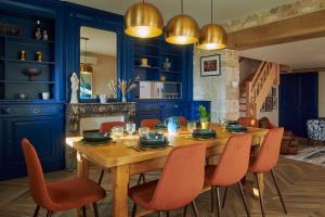 Le Vaudreuil的住宿－LE CLOS 1899，配有木桌和橙色椅子的用餐室