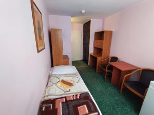 um pequeno quarto com uma cama e uma secretária em Jantar Economy em Szczecin