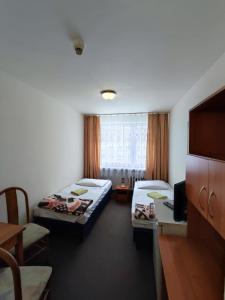 a room with two beds and a table and a tv at Jantar Economy in Szczecin