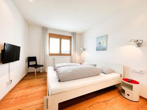 a white bedroom with a bed and a chair at Chalet Oberstaufen in Oberstaufen