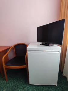 uma televisão em cima de um frigorífico branco com uma cadeira em Jantar Economy em Szczecin