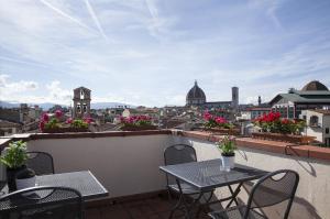 a balcony with tables and chairs and a view of a city at Locanda Dei Guelfi in Florence