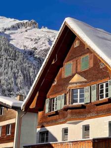 dom z śniegiem na dachu z górą w obiekcie Alpine Chalet w mieście Kandersteg