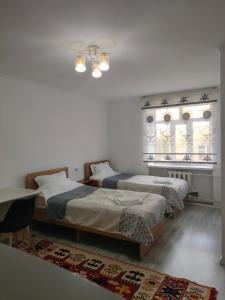 Un dormitorio con dos camas y una mesa. en Bayir Studio Apartment, en Karakol