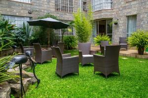 un gruppo di sedie e un ombrellone sull'erba di Batians Apartment Hotel a Nairobi