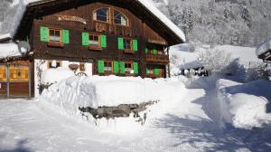 a house covered in snow with a pile of snow at Haus Älpele in Klösterle am Arlberg