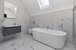 ein weißes Badezimmer mit einer Badewanne und einem Waschbecken in der Unterkunft Luxury 4-bed home with club room in Wilmslow