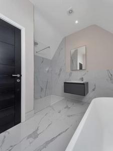 ein weißes Badezimmer mit einem Waschbecken und einem Spiegel in der Unterkunft Luxury 4-bed home with club room in Wilmslow
