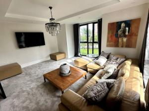 ein Wohnzimmer mit einem Sofa und einem Tisch in der Unterkunft Luxury 4-bed home with club room in Wilmslow