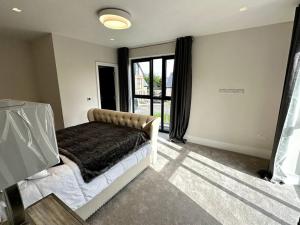 ein Schlafzimmer mit einem Bett und einem großen Fenster in der Unterkunft Luxury 4-bed home with club room in Wilmslow