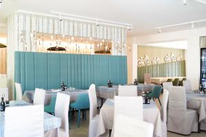 una sala da pranzo con tavoli e sedie bianche di Junior Family Hotel a Cavallino-Treporti