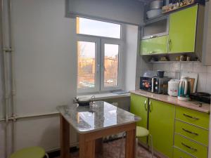 una cocina con armarios verdes, una mesa y una ventana en Bayir Studio Apartment, en Karakol