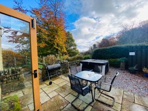 a patio with a table and chairs and a grill at Clara Cottage in Eyam