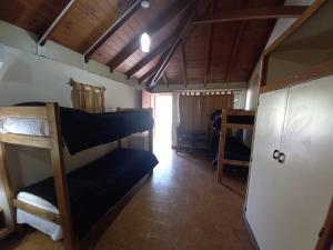 a room with bunk beds and a room with a door at Hostal de Los Andes in Rodeo de la Cruz