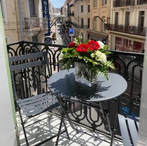 a table with a vase of flowers on a balcony at Alba apartment antibes street, by Welcome to Cannes in Cannes