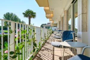 una fila de mesas y sillas en un balcón con una palmera en Junior Family Hotel, en Cavallino-Treporti