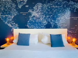 a bed with blue pillows and a map of the world at Fly Inn Apartment Berlin in Schönefeld