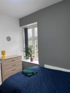 a bedroom with a blue bed and a dresser and a window at Westend Villas in Leicester