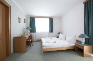 Habitación de hotel con cama, escritorio y ventana en Horský pension Gendorf en Cerny Dul