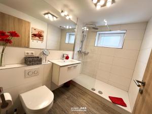 a white bathroom with a shower and a toilet at villa kunterBUNT in Grödersby +26 photos