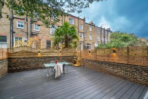 a wooden deck with a table and a building at NIRU Experience Urban Escape 1BR Retreat in London