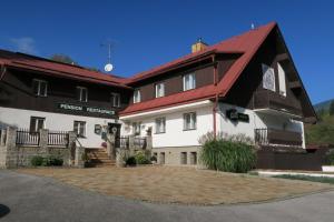 un grand bâtiment noir et blanc avec un toit rouge dans l'établissement Horský pension Gendorf, à Černý Důl