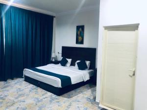 a bedroom with a large bed with blue curtains at افضل واحد للوحدات السكنية المخدومة - بست ون in Ad Dawādimī