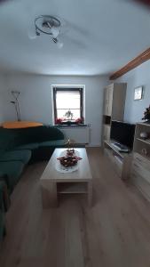 a living room with a green couch and a coffee table at Ferienwohnung am Querweg in Bockau