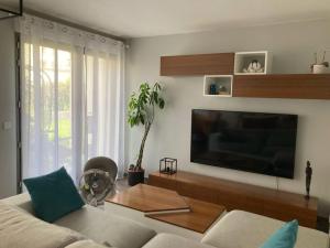 uma sala de estar com um sofá e uma grande televisão de ecrã plano em Maison proche de Versailles JO2024 em Saint-Cyr-lʼÉcole