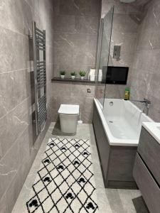 a bathroom with a tub and a toilet and a sink at Elegant 3 Bed Flat in Ramsgate in Kent