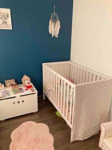 a baby room with a crib and a blue wall at Maison proche de Versailles JO2024 in Saint-Cyr-lʼÉcole