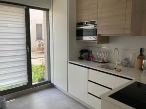 uma cozinha com armários brancos e uma janela em Maison proche de Versailles JO2024 em Saint-Cyr-lʼÉcole