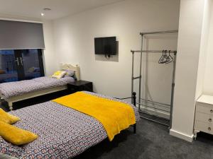 KentにあるElegant 3 Bed Flat in Ramsgateのベッドルーム1室(ベッド2台、壁掛けテレビ付)