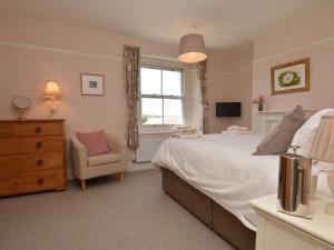 a bedroom with a bed and a chair and a window at 3 Bed in Bothenhampton DC160 in Bridport