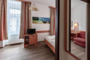 um quarto de hotel com uma cama, uma cadeira e um espelho em Hotel Admiral em Viena