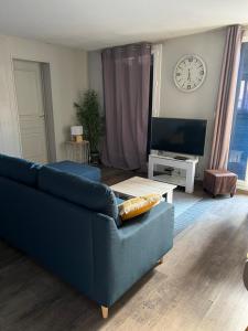 sala de estar con sofá azul y reloj en Maison du Lavoir Disneyland, en Bailly-Romainvilliers